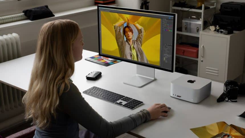 A person is using an Apple computer at a desk with a monitor, keyboard, and mouse.
