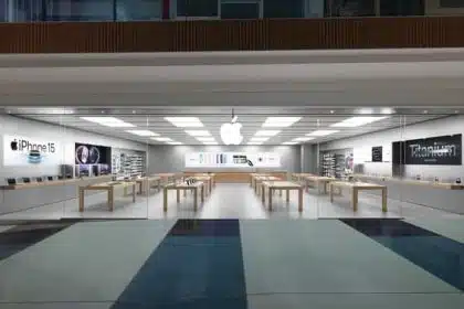 A modern Apple Store with glass walls, wooden tables, and Apple products on display.