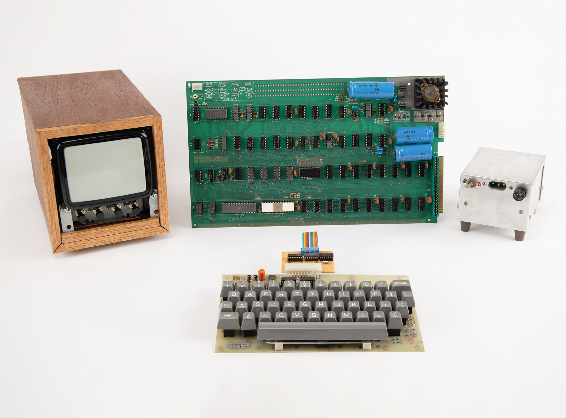 Vintage Apple-1 computer with monitor, circuit board, keyboard, and power supply.