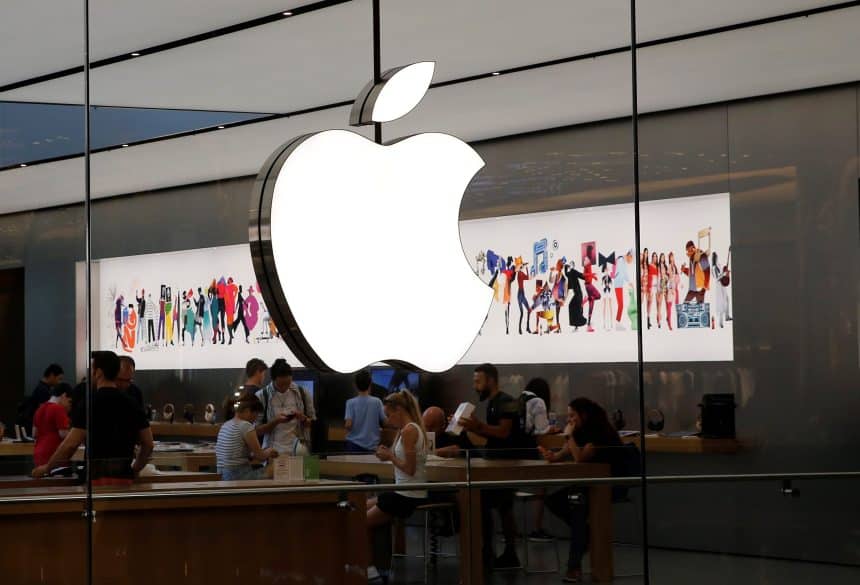 People browsing inside an Apple Store with a large Apple logo above.