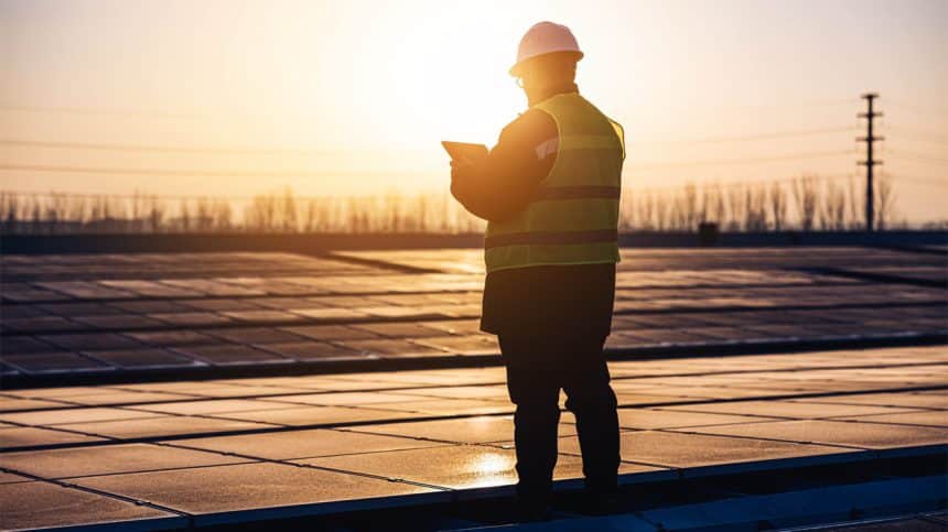 Engineer inspecting solar panels at sunset on a renewable energy site.