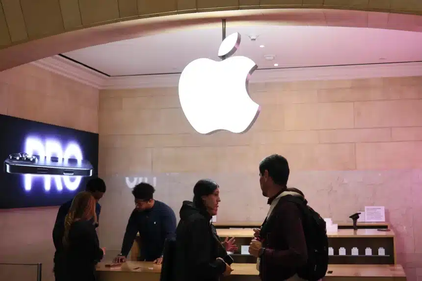 Customers inside an Apple Store under a glowing Apple logo.