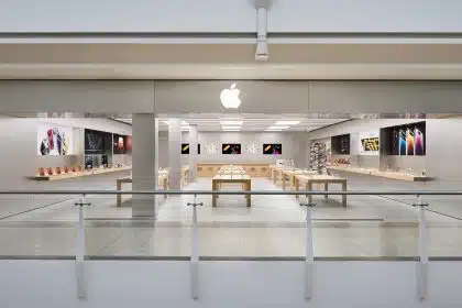 Apple retail store in the UK with product displays and large wall screens.