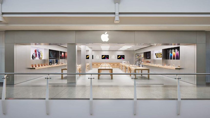 Apple retail store in the UK with product displays and large wall screens.