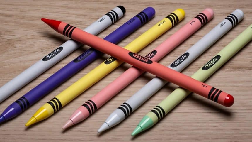 Colourful Apple Pencil Pro models styled to look like crayons on a wooden surface.