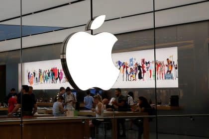 People inside an Apple Store with a large glowing Apple logo.