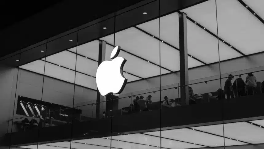 Apple logo on a glass storefront with people inside the store.