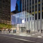 Apple Store with glass entrance in a city plaza at night.
