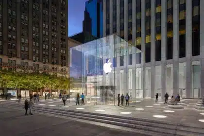 Apple Store with glass entrance in a city plaza at night.