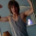 Man flexing in mirror with photographer’s reflection in background.