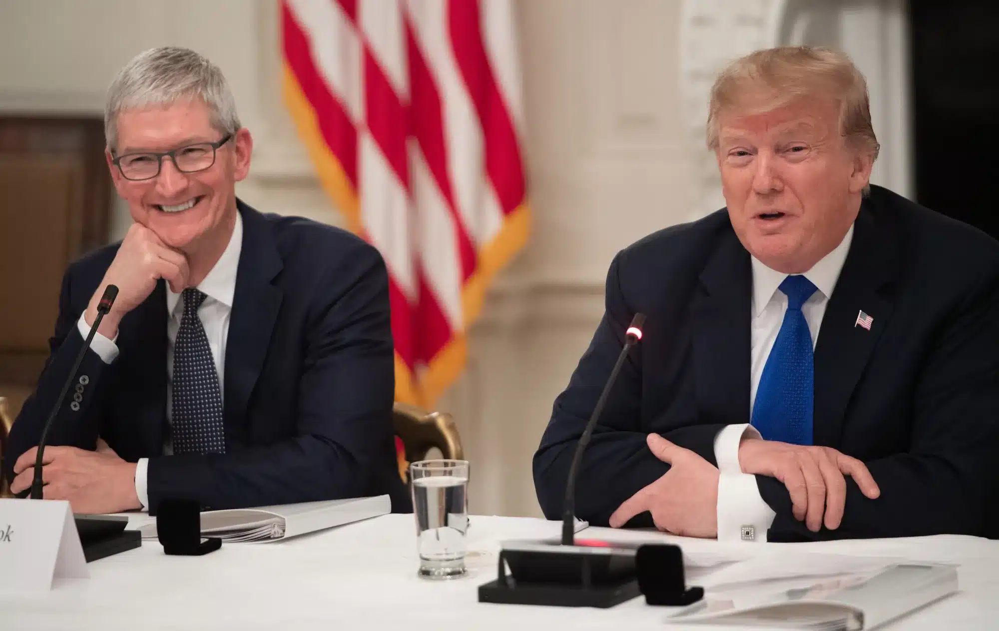 Tim Cook and Donald Trump speaking at a meeting.