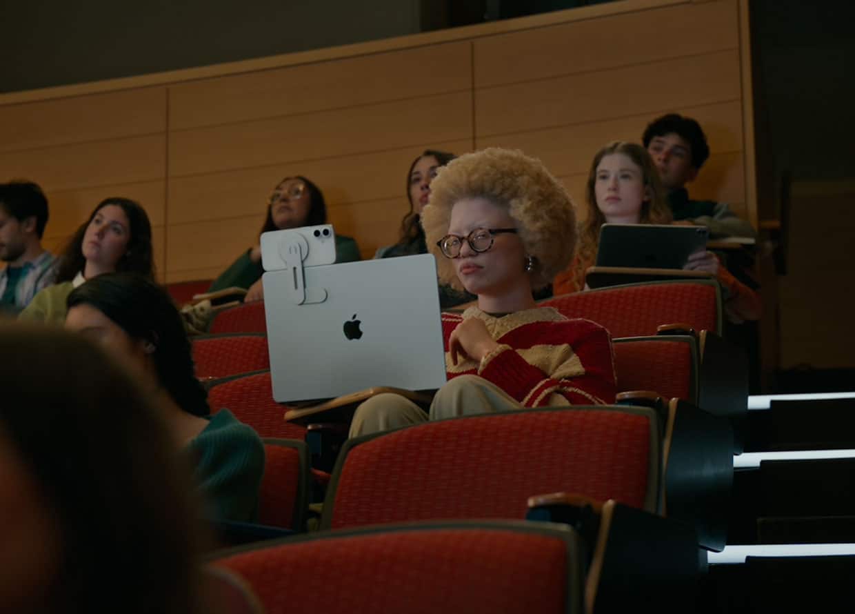 Student using iPhone and MacBook with accessibility tools in a lecture hall.