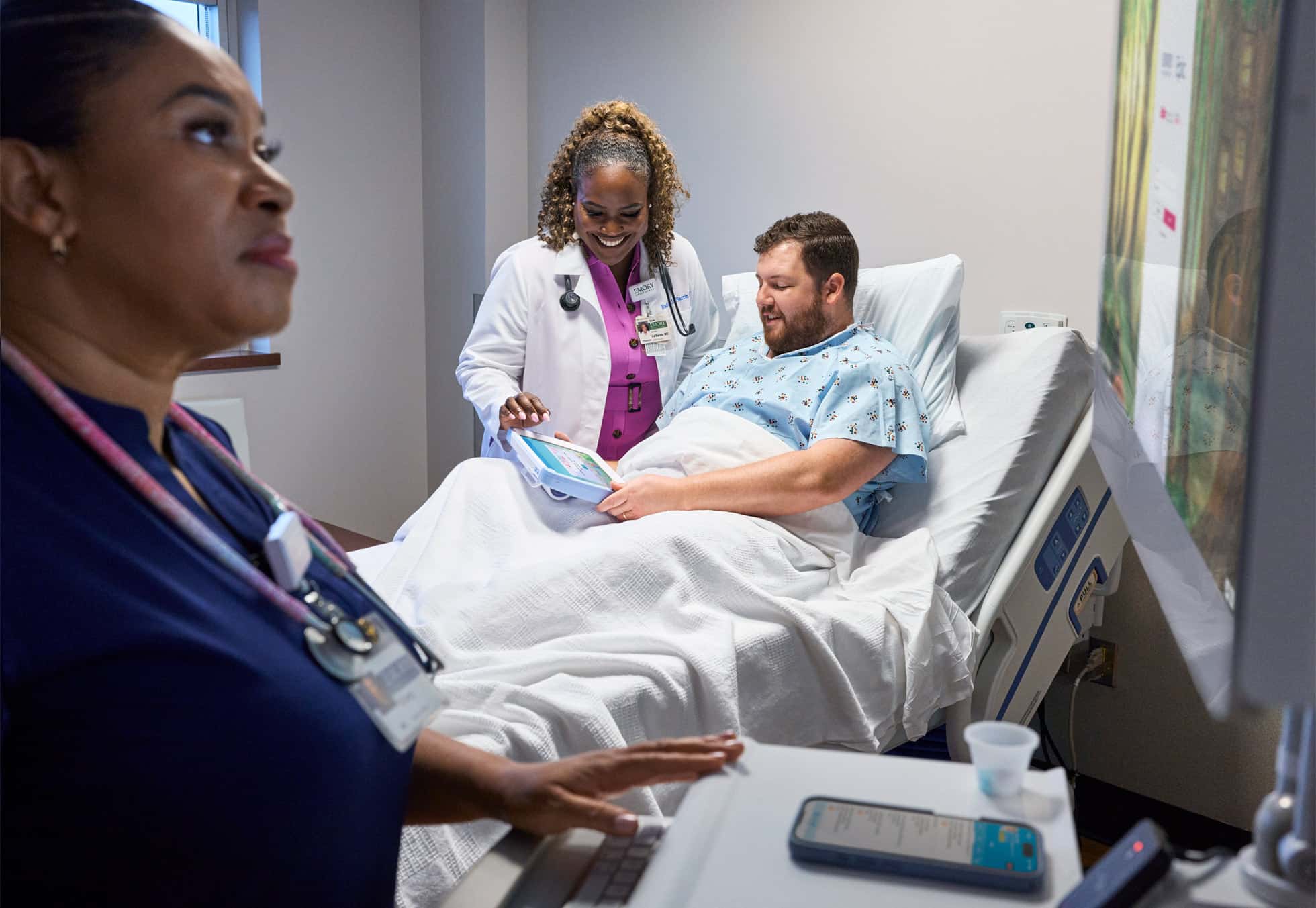 Doctor and patient using an iPad at Emory Hospital bedside.