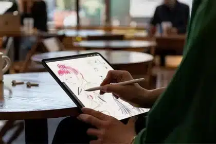 Person drawing on an iPad with Apple Pencil in a café setting.