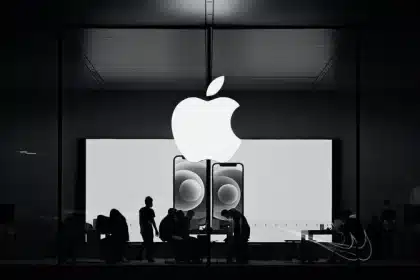 Silhouettes of people inside an Apple Store with a large Apple logo overhead.