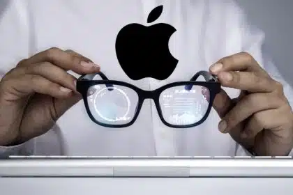 Person holding Apple smart glasses with digital data reflected in the lenses.