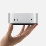 Hand holding a compact silver M4 Mac Mini computer.