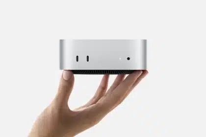 Hand holding a compact silver M4 Mac Mini computer.