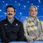 Jason Sudeikis and Hannah Waddingham sitting in stadium seats during "Ted Lasso" scene.