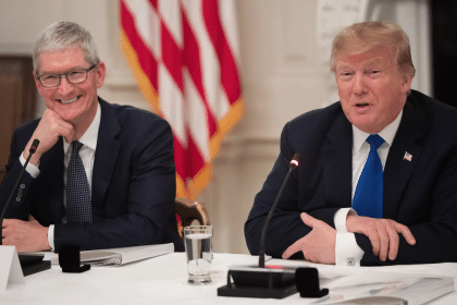 Tim Cook and Donald Trump seated at a meeting, speaking with microphones.