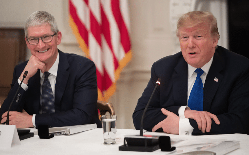 Tim Cook and Donald Trump seated at a meeting, speaking with microphones.