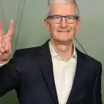 Tim Cook smiling and making a peace sign gesture.