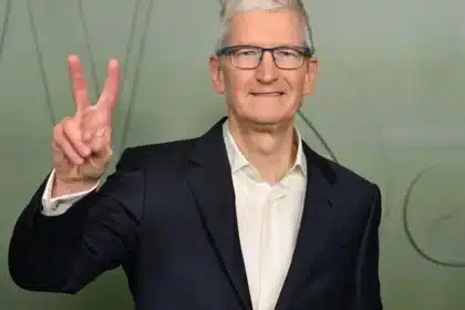 Tim Cook smiling and making a peace sign gesture.