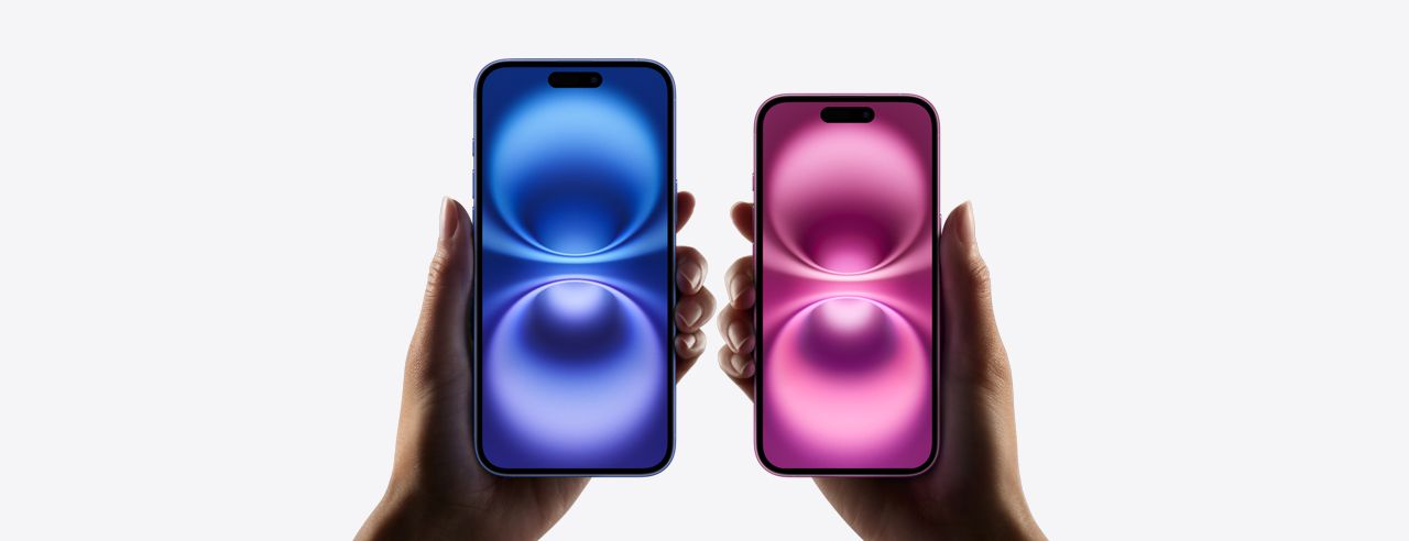Two hands holding blue and pink Apple iPhones against a white background.