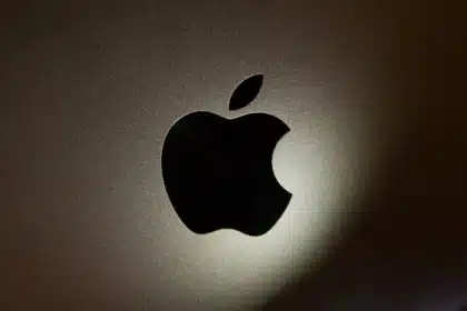 Close-up of a black Apple logo on a metallic surface with soft lighting.
