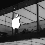 Apple logo on glass wall of a modern Apple Store.