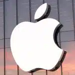 Apple logo on the glass exterior of a corporate building during sunset.