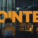 A student in a hoodie uses a MacBook in a dimly lit dorm room with the word "POINTED" in bold text.