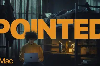 A student in a hoodie uses a MacBook in a dimly lit dorm room with the word "POINTED" in bold text.