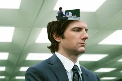 A man in a suit with a miniature version of himself working at a desk inside his head, from the show Severance.