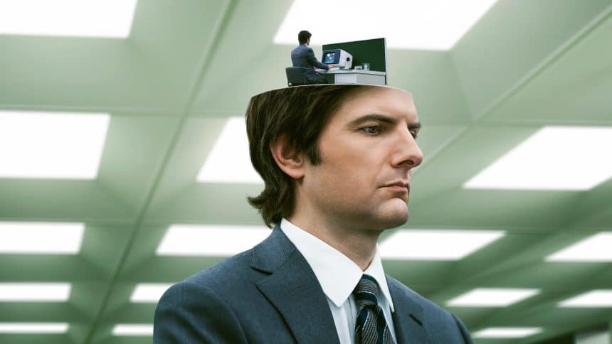 A man in a suit with a miniature version of himself working at a desk inside his head, from the show Severance.