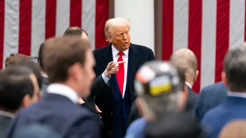 Donald Trump speaking to a crowd in front of a U.S. flag backdrop.
