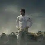 Brad Pitt stands in front of a Formula 1 race car in the movie F1.
