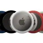 Five Apple AirTags in coloured covers (blue, black, white, red, green) fanned out on a white background.