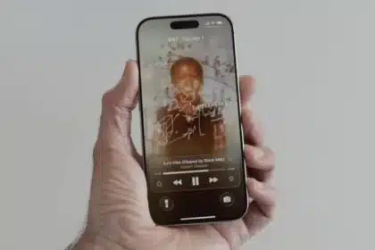 Hand holding an iPhone showing animated album art and music controls on the lock screen.