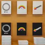Stacks of Apple Park merchandise boxes beneath framed retro rainbow and monochrome Apple logos.