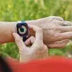 Person checking activity rings on an Apple Watch outdoors.