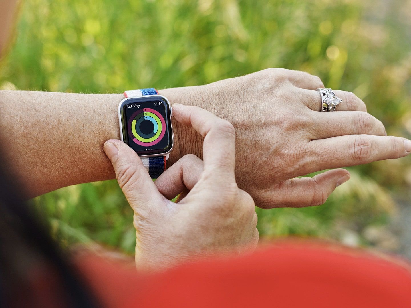 Person checking activity rings on an Apple Watch outdoors.