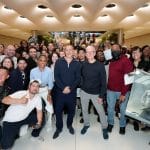 Brad Pitt and Tim Cook standing amid a cheering crowd inside Apple Fifth Avenue during an F1 movie promotion.