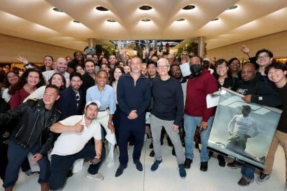 Brad Pitt and Tim Cook standing amid a cheering crowd inside Apple Fifth Avenue during an F1 movie promotion.