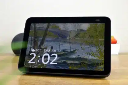 A tabletop smart display showing the time, date, and weather over a Van Gogh–style art wallpaper.