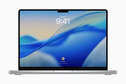 MacBook Pro lock screen with blue wave wallpaper, digital clock at top, and user avatar at bottom.