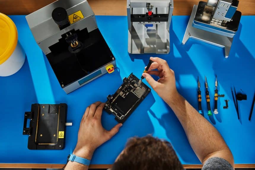 Technician repairing an iPhone on a workbench.