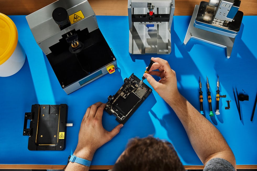 Technician repairing an iPhone on a workbench.