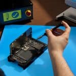 Technician unscrewing an open iPhone on a repair bench.