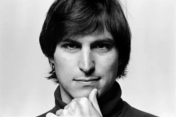 Black-and-white close-up portrait of Steve Jobs resting his chin on his hand.